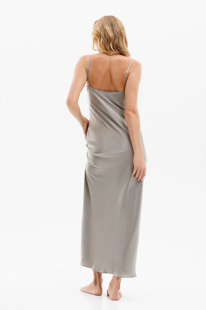 Woman wearing a long silk gray slip dress on a spaghetti straps showing the back pose. 