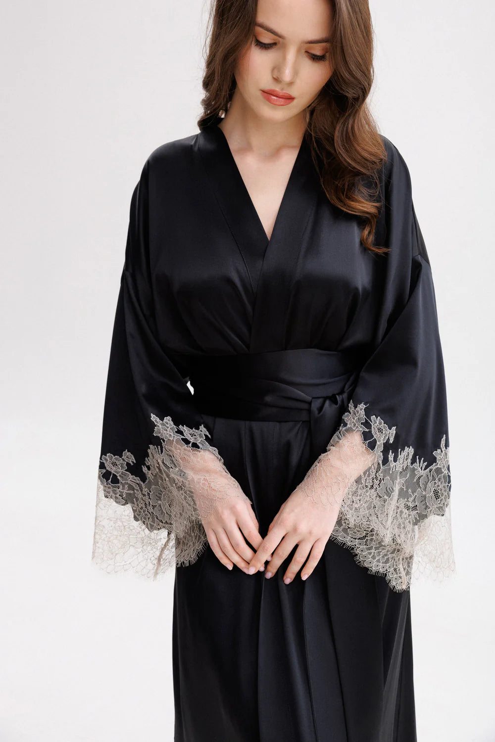 Woman wearing a long classy silk kimono stile dressing gown with floral Leavers Lace embroidery. Silk wide long belt giving the touch of the unique stile. Full front picture.