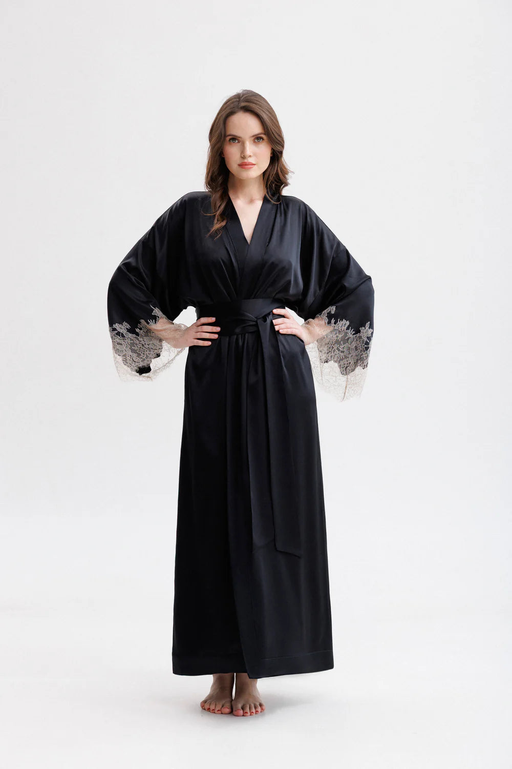 Woman wearing a long classy silk kimono stile dressing gown with floral Leavers Lace embroidery. Silk wide long belt giving the touch of the unique stile. Full front picture.