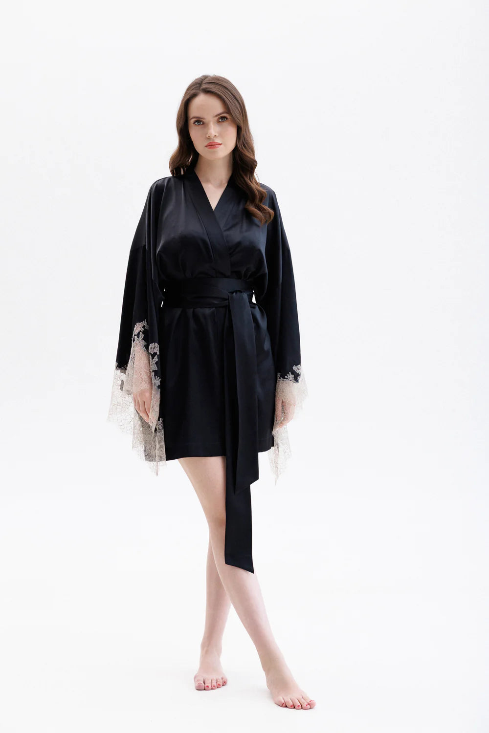 Woman wearing a black short silk robe with Leavers Lace sleeves showing the elegance of the sleaves. Long wide belt is completing the look.