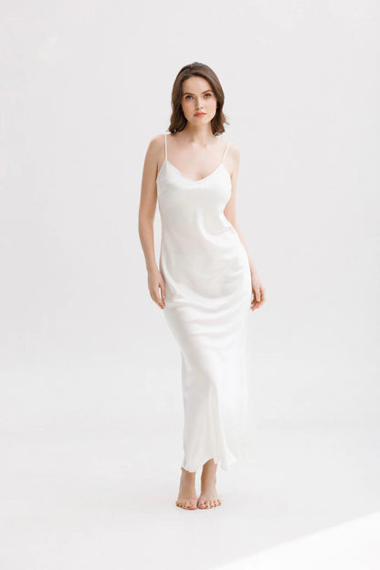 Woman wearing a long silk white slip dress on a spaghetti straps showing the front pose. 